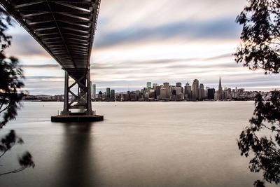 Bridge over river against cloudy sky