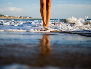 Low section of woman wading in sea