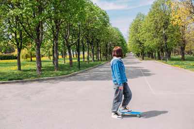 Young stylish woman wears sunglasses walks on the street with a skateboard