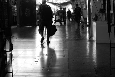 Rear view of people walking on tiled floor in city