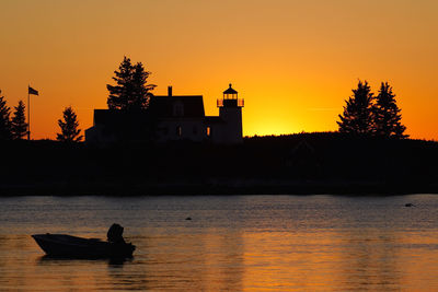 Silhouette boat in lake against orange sky