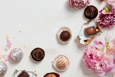 Still life of open chocolates and wrappers with flowers