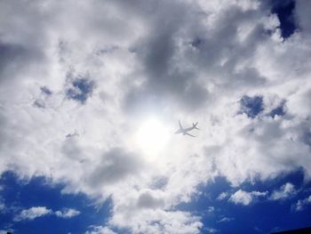 Low angle view of airplane flying against cloudy sky