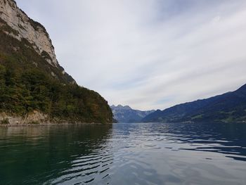 Scenic view of lake by mountains against sky