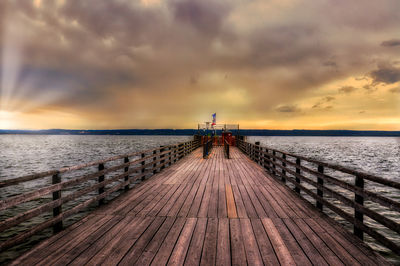 Pier over sea against sky during sunset