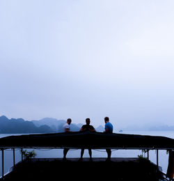 Men standing on railing against clear sky