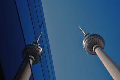 Low angle view of television tower against sky with reflection of a building