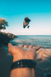 Close-up of person flying over sea against sky