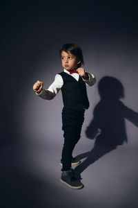 Stylish boy child of four years in the studio on the background in a vest and a red bow tie