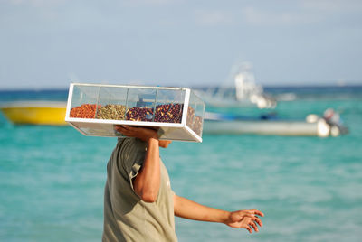 Midsection of woman holding ice cream against sea