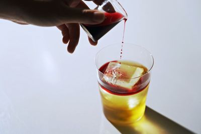 Moment of pouring red wine into drink on white background