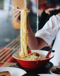 Cropped image of woman having spaghetti at table