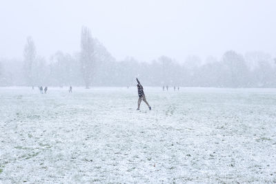 Person on snow covered land against sky