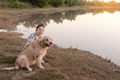 Woman with dog sitting by lake