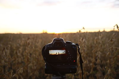 Close-up of camera on field against sky during sunset