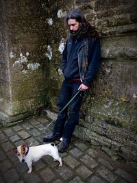 Full length of man with dog standing against wall