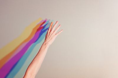 Close-up of hand holding colored pencils over white background