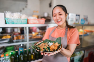 Portrait of smiling young woman having food in store