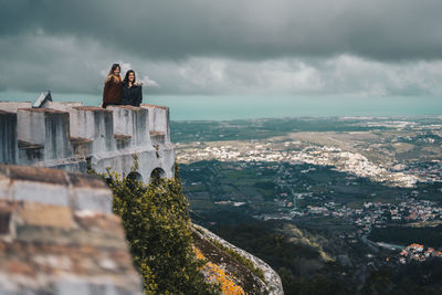 Friends standing on castle against cloudy sky