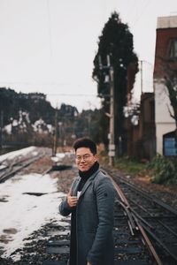 Portrait of man standing on railroad track against sky