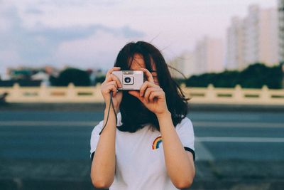 Portrait of woman photographing camera on smart phone