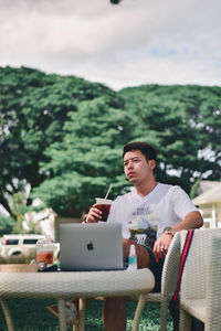 Young man using phone while sitting on table