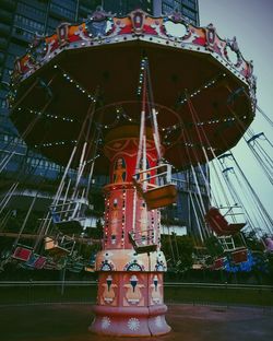 Low angle view of chain swing ride against sky