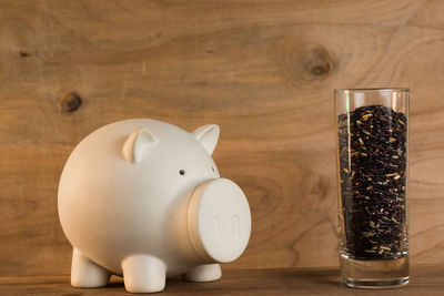 Close-up of piggy bank and food in glass on table
