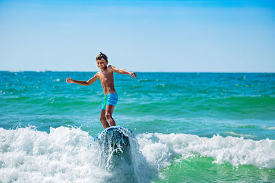 Full length of young woman jumping in sea against clear sky