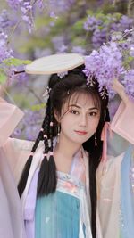 Portrait of smiling young woman standing against flowers