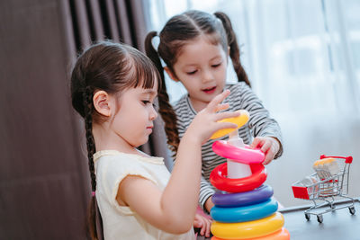 Sisters playing with multi colored toys at home