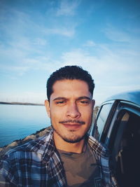 Portrait of man by car against sky