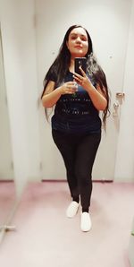 Full length of young woman using mobile phone