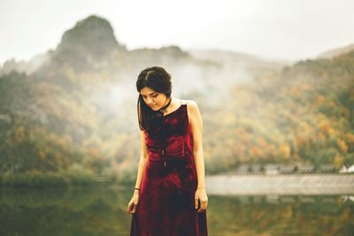 Portrait of woman in red dress against mountain