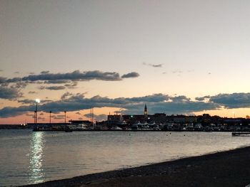 City by sea against sky during sunset