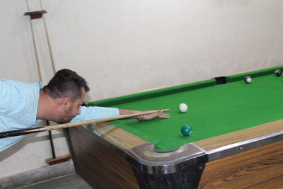 Side view of man playing snooker in room