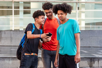 Young man showing smart phone to friends outdoors