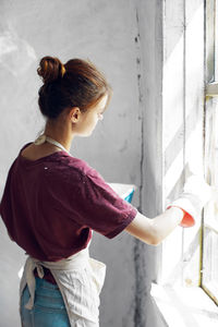 Side view of woman standing against wall