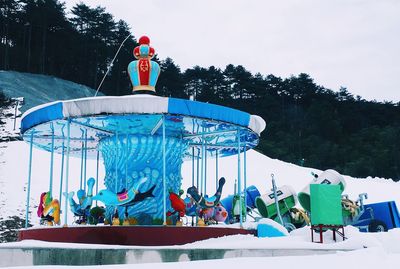 People at amusement park against sky