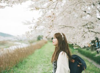 Thoughtful woman standing by cherry tree in park