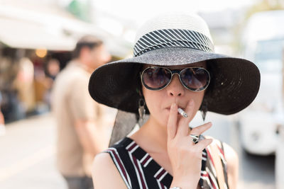 Portrait of woman smoking cigarette in city 