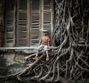 Boy sitting on window sill by roots