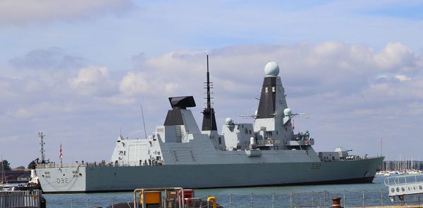 Ship moored at harbor against sky