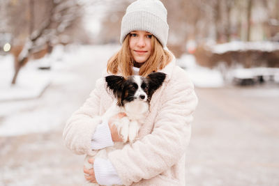 Portrait of girl holding dog while standing outdoors