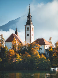 Church amidst trees and buildings against sky