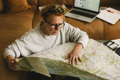 High angle view of elderly woman planning trip on map in living room