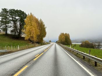 Road amidst trees against clear sky