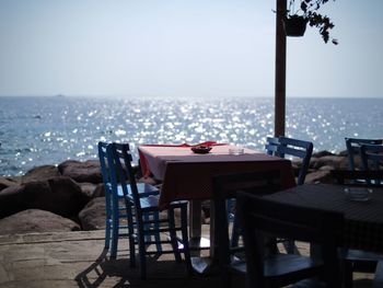 Empty chairs and table at restaurant against horizon