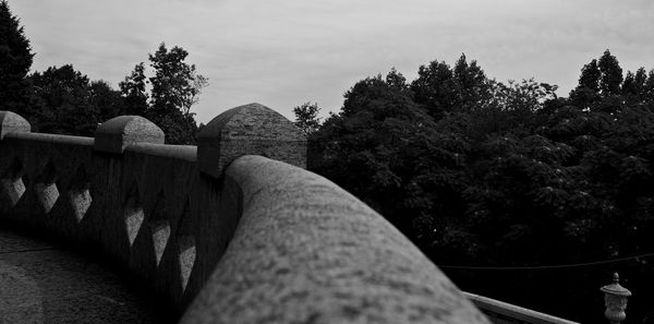 Close-up of hand by retaining wall against sky