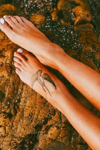 Low section of woman with tattoo on rock